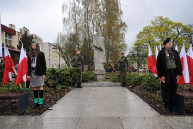 Na zdjęciu widzimy dwóch żołnierzy i dwóch harcerzy obok pomnika J.Kilińśkiego. Widać też zieleń miejską i polskie flagi.